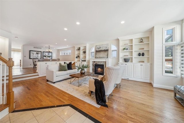 living room with a wealth of natural light, light wood-type flooring, visible vents, and a glass covered fireplace