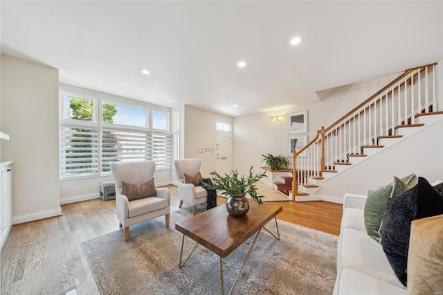 living area featuring a wealth of natural light, stairs, and light wood finished floors