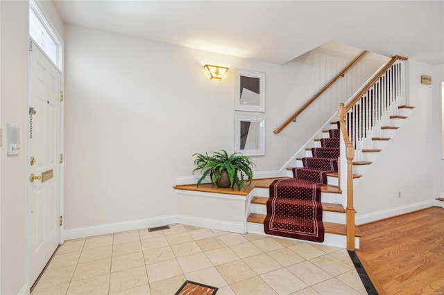 foyer featuring tile patterned floors, visible vents, baseboards, and stairway