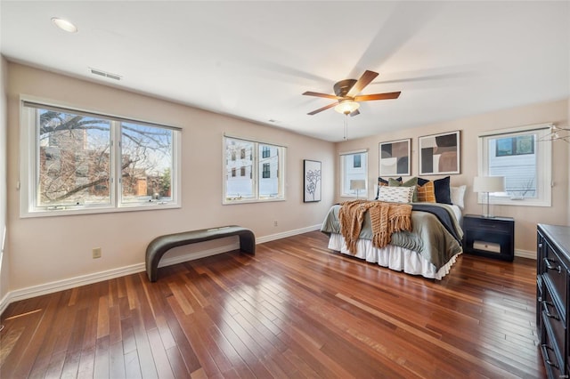 bedroom with dark wood-style floors, visible vents, a ceiling fan, and baseboards