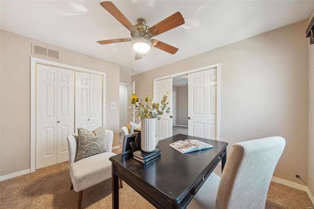 carpeted office space with visible vents, a ceiling fan, and baseboards