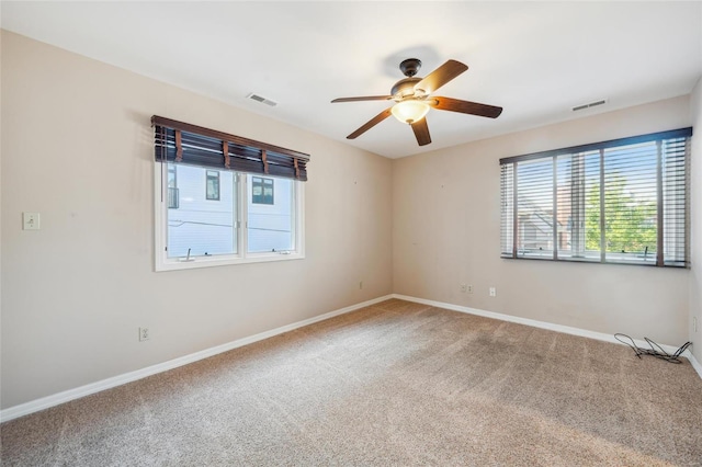 carpeted empty room with a ceiling fan, baseboards, and visible vents