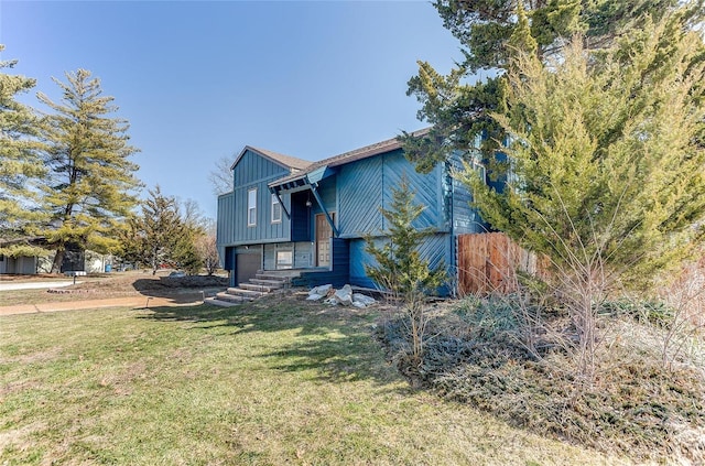 view of front of house featuring a front lawn, board and batten siding, an attached garage, and fence