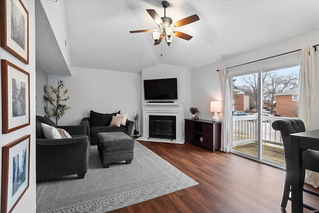 living room with wood-type flooring, vaulted ceiling, a textured ceiling, and ceiling fan