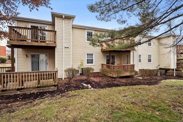 rear view of property with a balcony, a deck, and a lawn