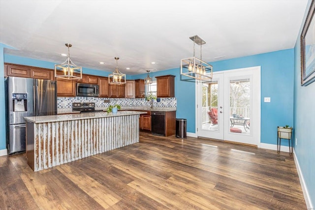 kitchen featuring appliances with stainless steel finishes, backsplash, a kitchen island, decorative light fixtures, and french doors