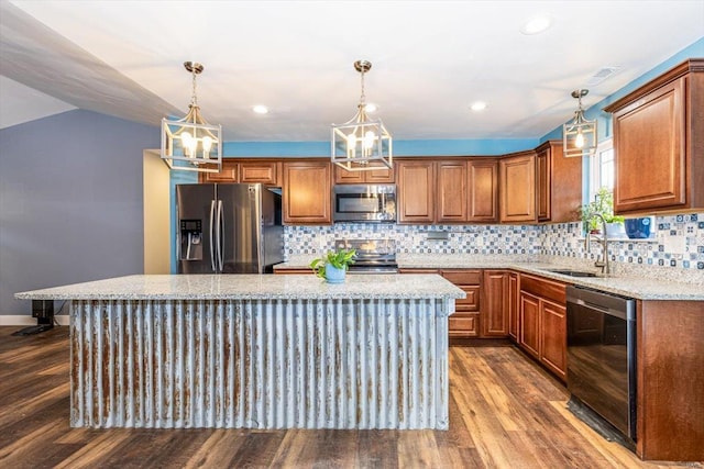 kitchen with hanging light fixtures, light stone countertops, a center island, and appliances with stainless steel finishes