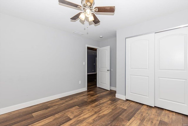 unfurnished bedroom with dark wood-type flooring, a closet, and ceiling fan