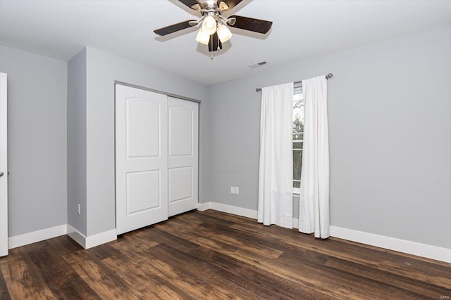 unfurnished bedroom featuring ceiling fan, dark hardwood / wood-style floors, and a closet