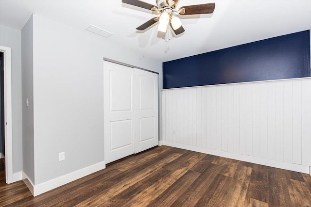 unfurnished bedroom featuring dark wood-type flooring, ceiling fan, and a closet