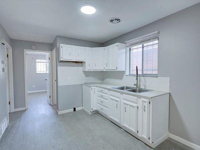 kitchen with sink, white cabinets, and light wood-type flooring