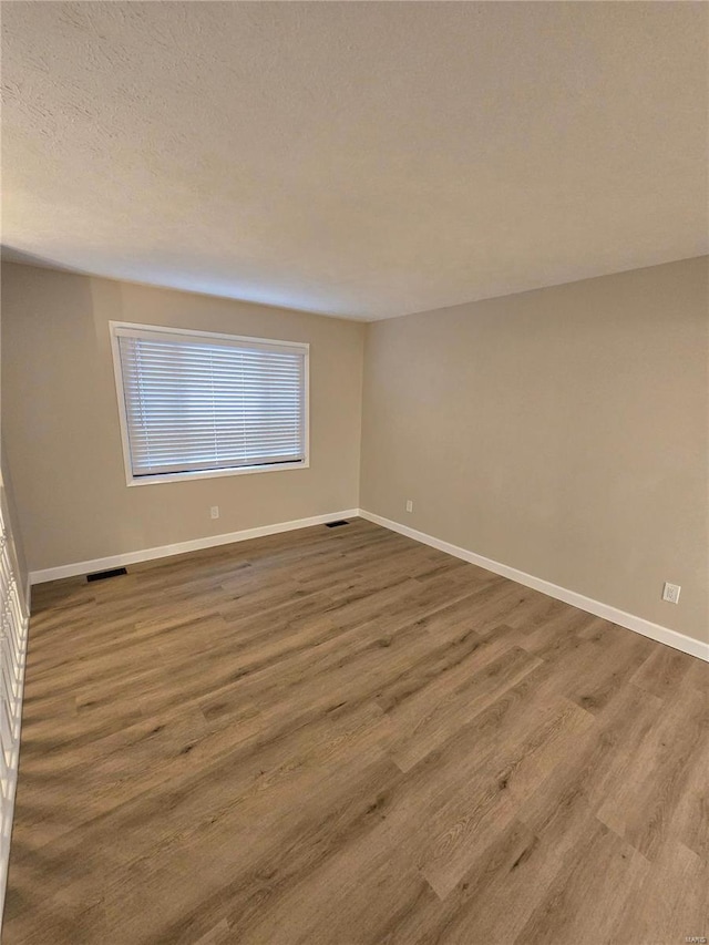 spare room featuring wood-type flooring and a textured ceiling