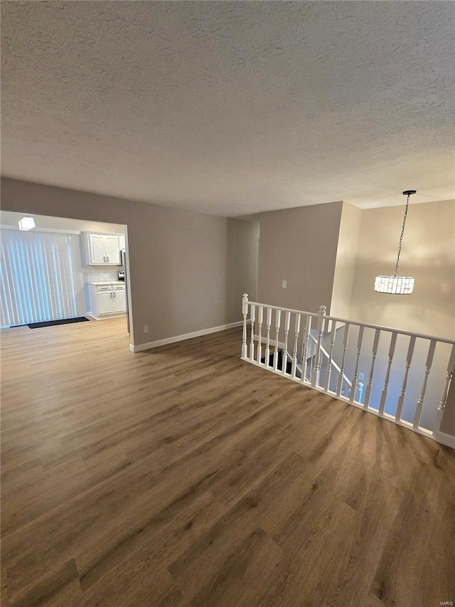 unfurnished room with wood-type flooring and a textured ceiling