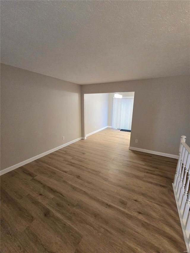 empty room with dark hardwood / wood-style floors and a textured ceiling