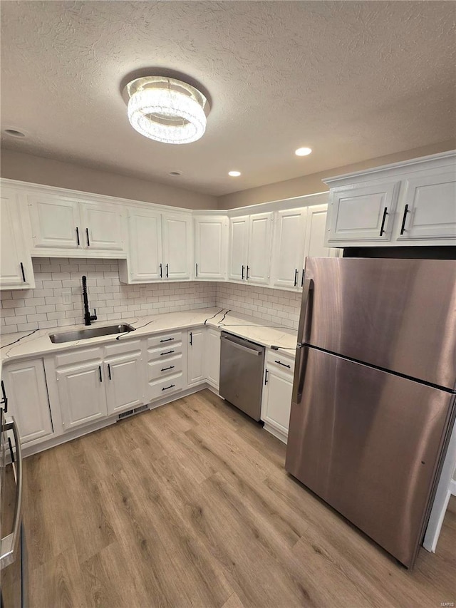 kitchen featuring white cabinetry, appliances with stainless steel finishes, sink, and light hardwood / wood-style floors