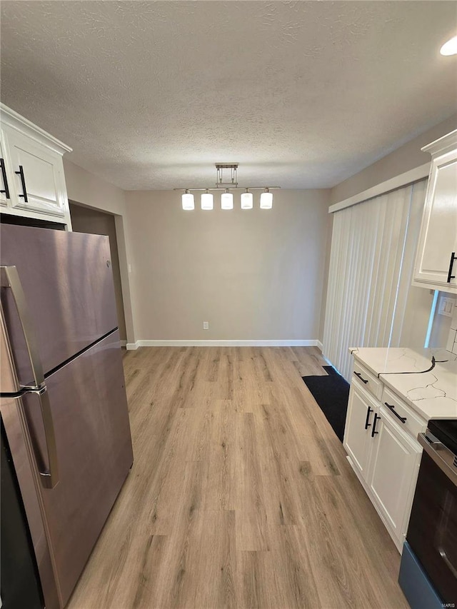 kitchen featuring electric range oven, light stone countertops, stainless steel refrigerator, and white cabinets