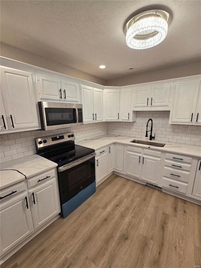 kitchen with stainless steel appliances, sink, light hardwood / wood-style flooring, and white cabinets