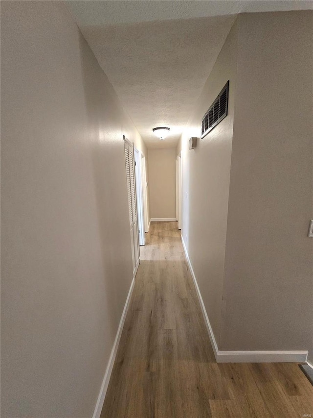 hallway featuring hardwood / wood-style flooring and a textured ceiling