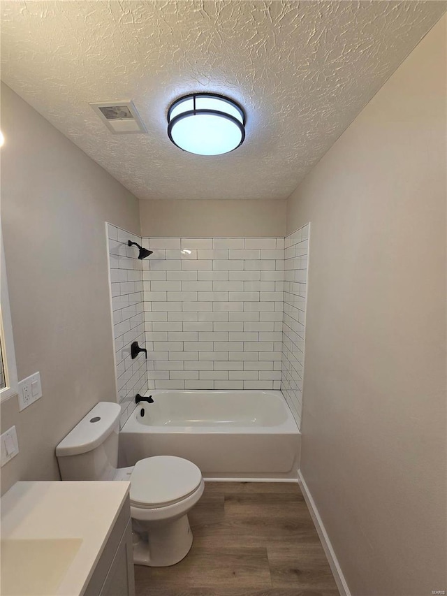 full bathroom with toilet, a textured ceiling, vanity, tiled shower / bath combo, and hardwood / wood-style floors