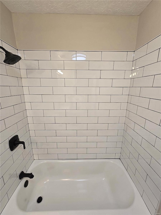 bathroom with tiled shower / bath and a textured ceiling