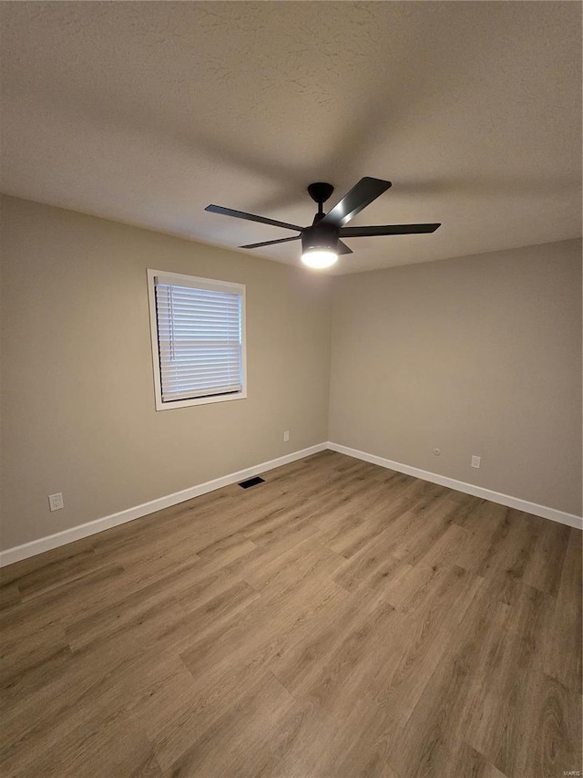 empty room featuring ceiling fan, wood-type flooring, and a textured ceiling