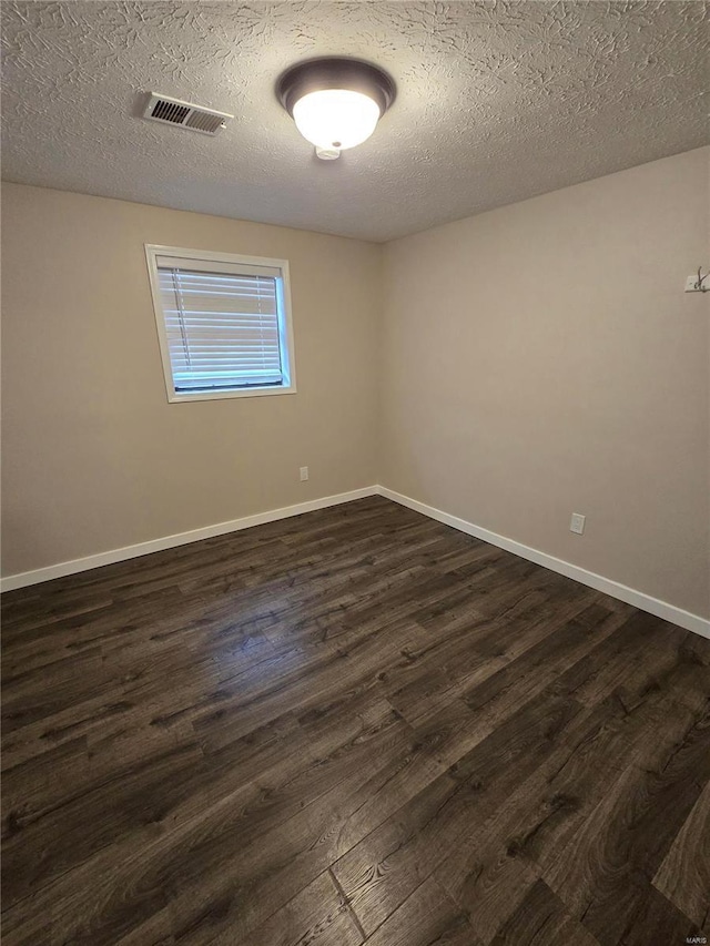 spare room with dark wood-type flooring and a textured ceiling