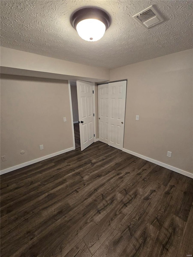 empty room featuring dark wood-type flooring and a textured ceiling