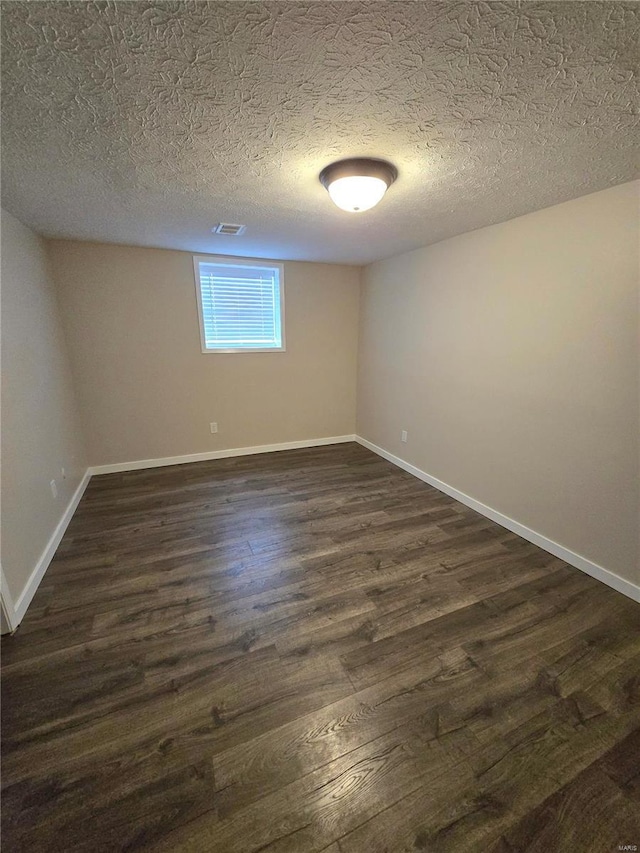 spare room featuring dark hardwood / wood-style floors and a textured ceiling