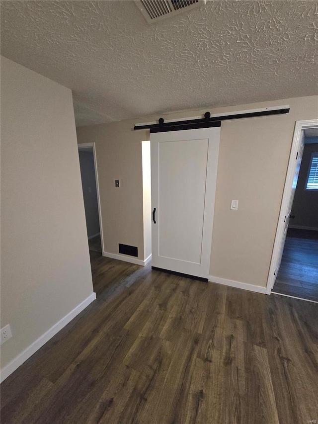 interior space with dark hardwood / wood-style flooring, a barn door, and a textured ceiling