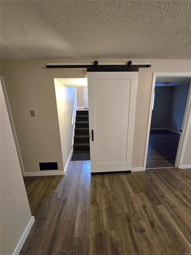 interior space with a barn door, dark wood-type flooring, and a textured ceiling