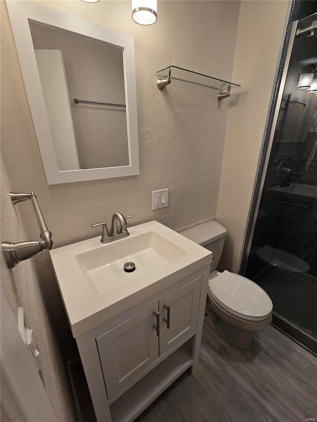 bathroom with vanity, toilet, hardwood / wood-style floors, and a shower