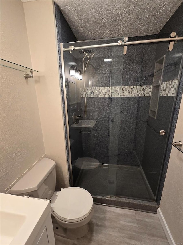 bathroom featuring hardwood / wood-style floors, vanity, walk in shower, toilet, and a textured ceiling