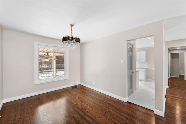 unfurnished dining area featuring an inviting chandelier, wood finished floors, visible vents, and baseboards