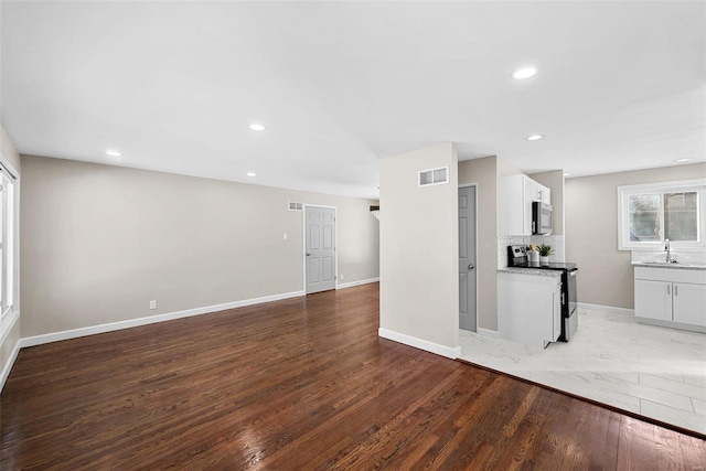 interior space featuring baseboards, visible vents, wood finished floors, and recessed lighting