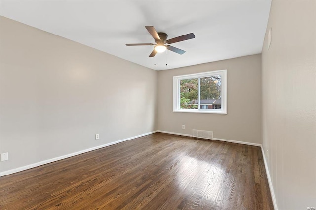 unfurnished room featuring a ceiling fan, visible vents, dark wood finished floors, and baseboards