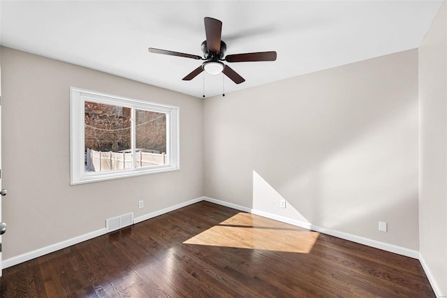 empty room featuring a ceiling fan, visible vents, baseboards, and wood finished floors