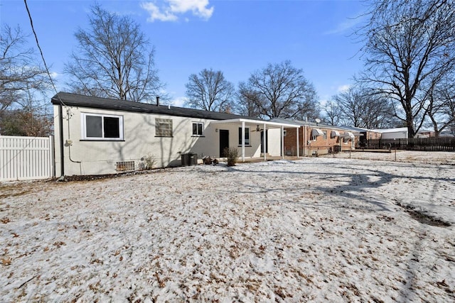 snow covered property with cooling unit, brick siding, and fence