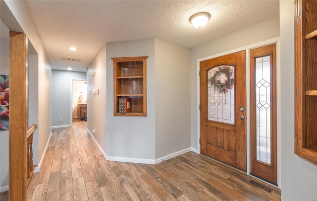 entryway featuring a healthy amount of sunlight, hardwood / wood-style floors, and a textured ceiling