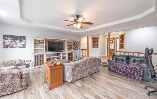 living room with ceiling fan, a raised ceiling, and light hardwood / wood-style floors