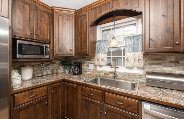 kitchen with appliances with stainless steel finishes, sink, backsplash, and decorative light fixtures