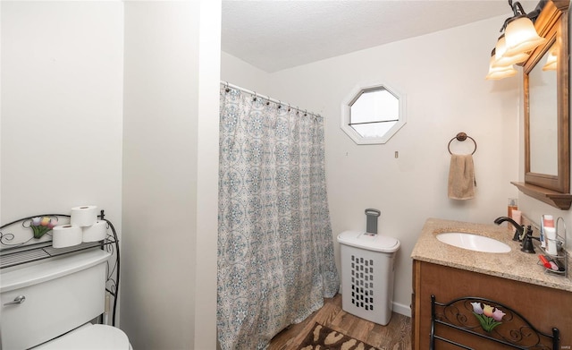 bathroom with vanity, a textured ceiling, wood-type flooring, and toilet