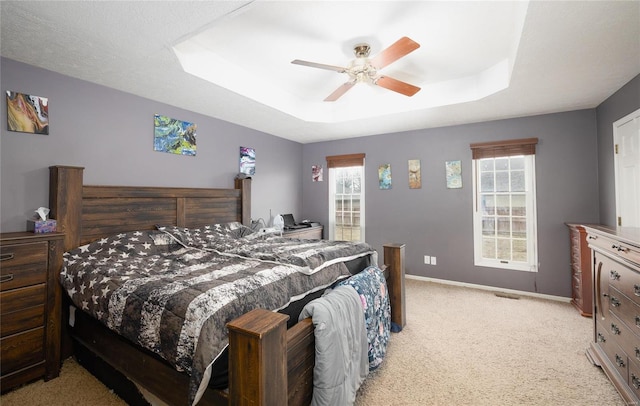 carpeted bedroom featuring ceiling fan and a raised ceiling