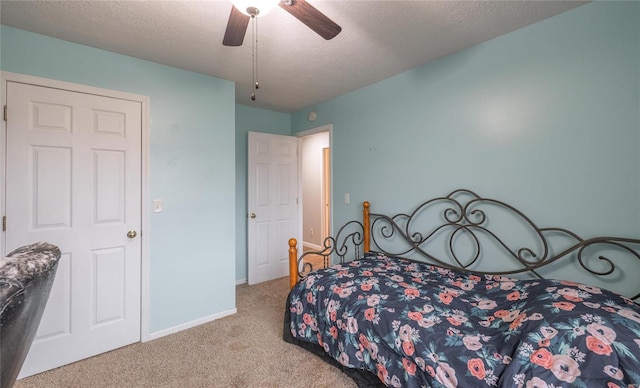 bedroom featuring ceiling fan, light colored carpet, and a textured ceiling