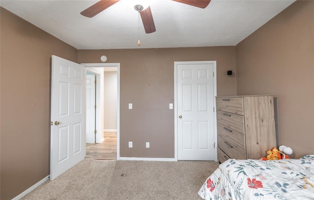 bedroom featuring ceiling fan, light colored carpet, and a textured ceiling