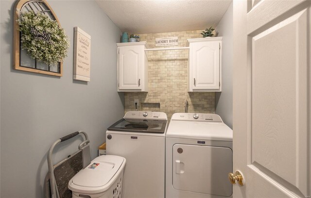 laundry room featuring cabinets, washing machine and clothes dryer, and a textured ceiling