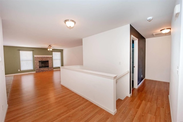 hallway with light wood-type flooring, baseboards, and an upstairs landing