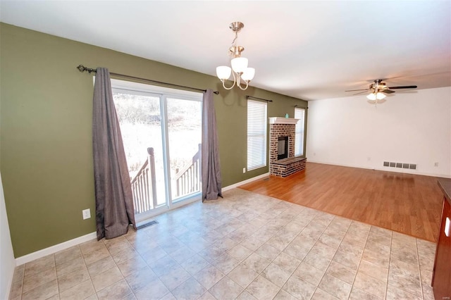 unfurnished living room with a fireplace, visible vents, and baseboards