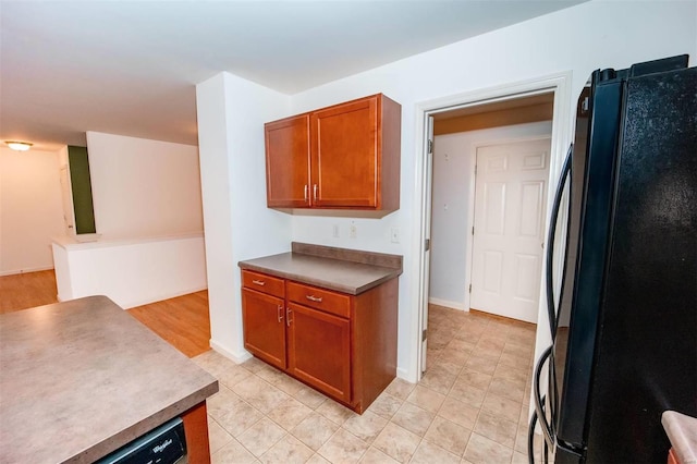 kitchen featuring baseboards, brown cabinetry, and freestanding refrigerator