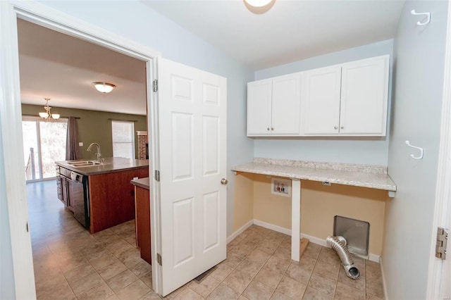 clothes washing area with laundry area, baseboards, and a sink