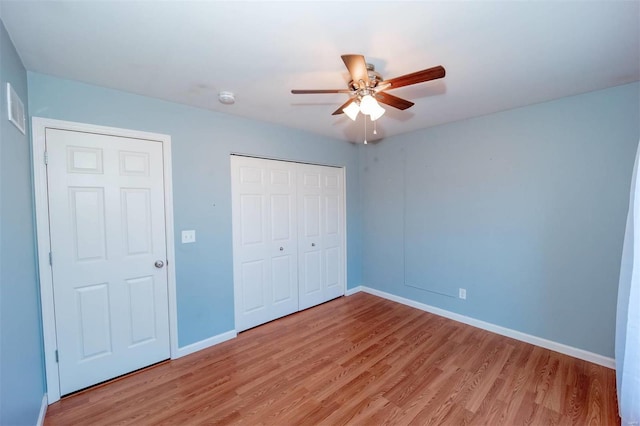 unfurnished bedroom with light wood-type flooring, a ceiling fan, baseboards, and a closet